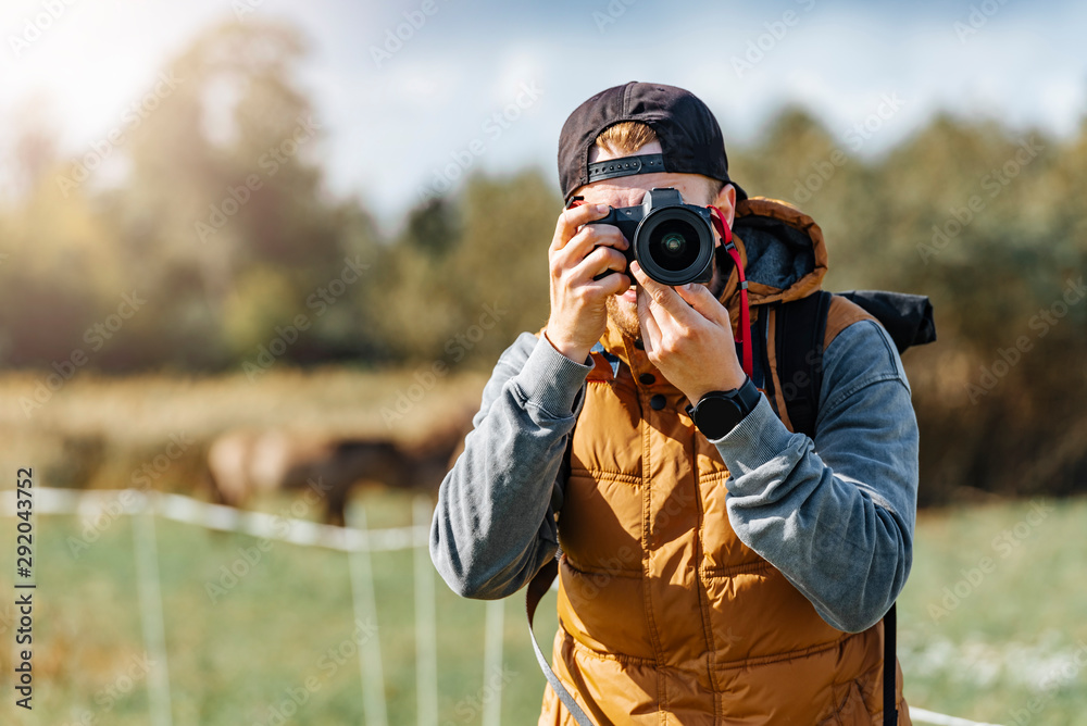 Photographer in brown vest and black hat taking pictures with his camera during sunny summer day. Photographer in brown vest and black hat taking pictures with his camera during sunny summer day.