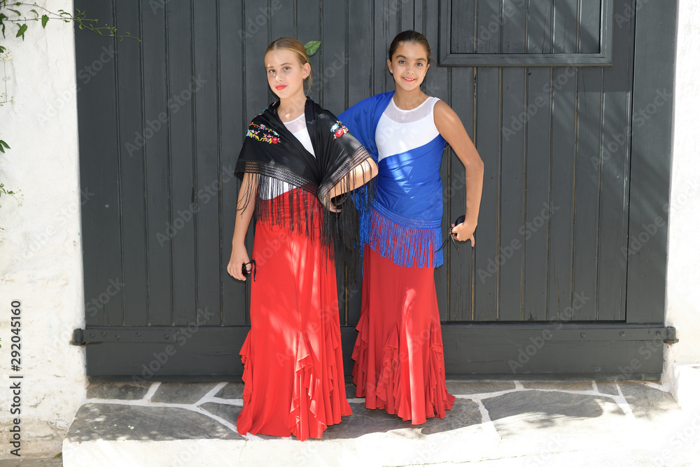 Two girls dancing flamenco. They are in a symmetrical position with the typical handkerchief and the castanets