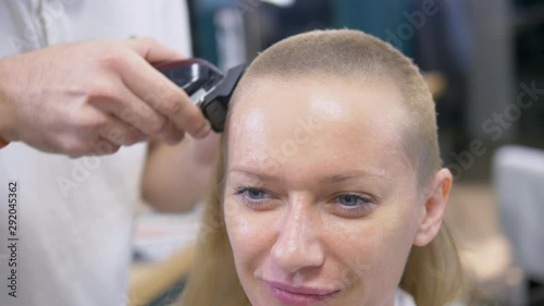 Woman shaving her head baldly. a hairdresser shaves a woman's long hair with a hair clipper. photo