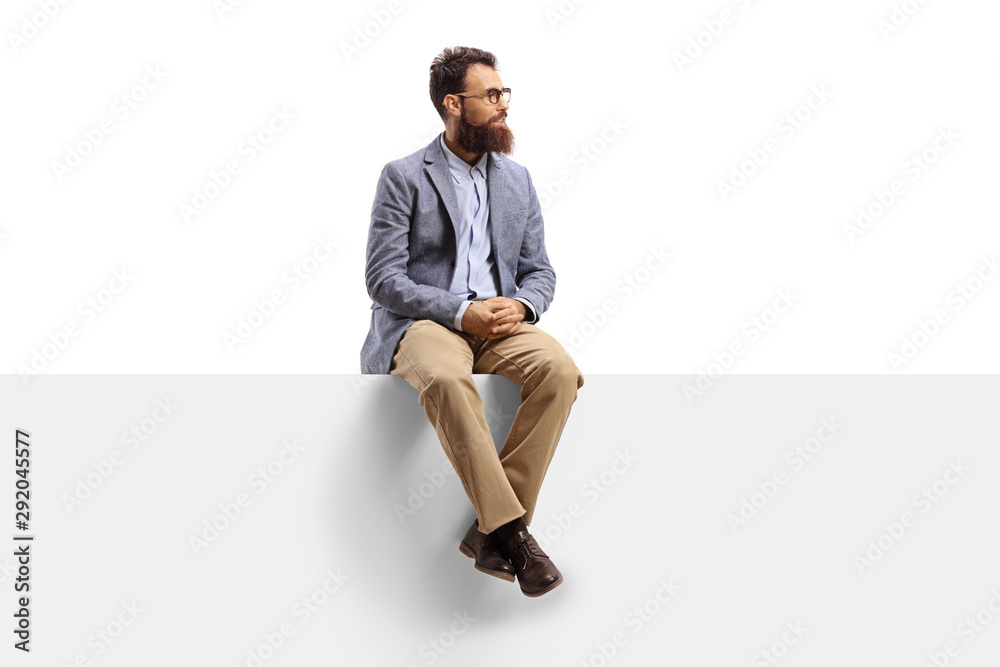 Bearded man sitting on a white banner and looking to the side - obrazy, fototapety, plakaty 