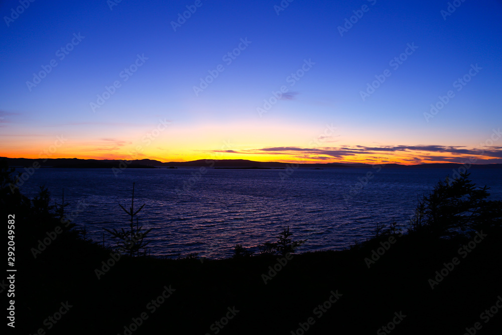 Sunsetting over the ocean with silhouette of the trees