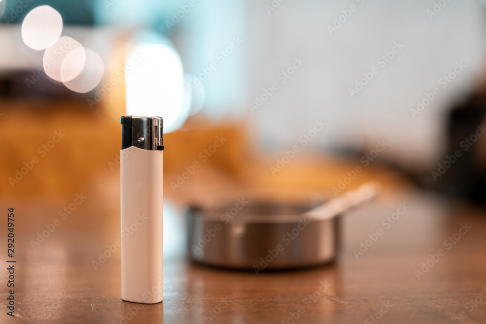lighter in front of blurred cigarette and ashtray. cheap cigarette