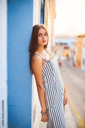 Fashion portrait of young elegant woman posing against the blue wall.