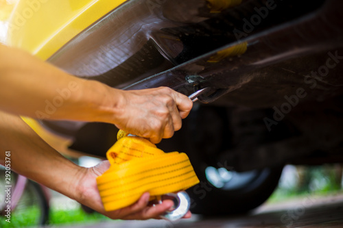 Canvastavla Hands of man holding yellow car towing strap with yellow car