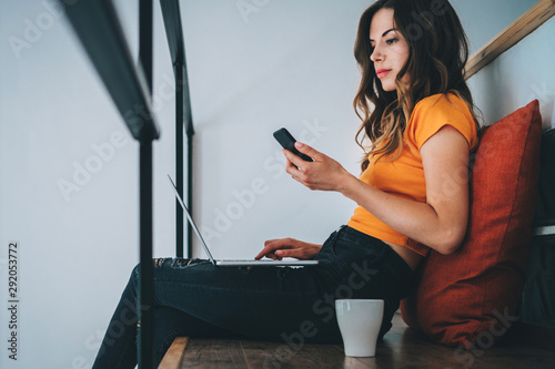 Female freelancer working at home using her laptop and mobile phone