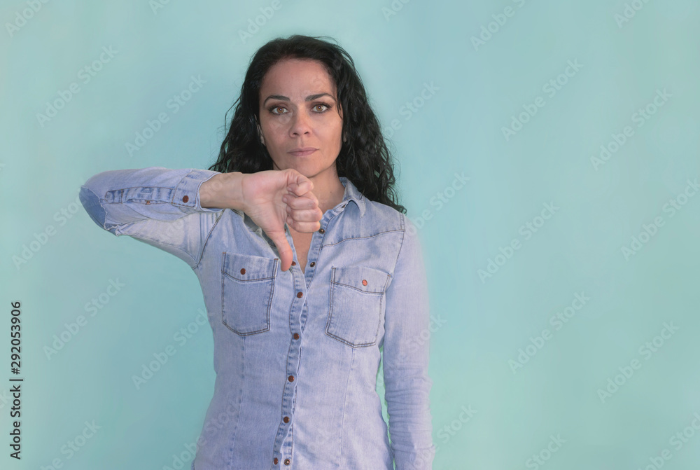 Brunette woman with thumb down showing disagreement Brunette woman with thumb down showing disagreement