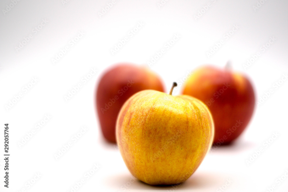 close up of a yellow apple with red apples in the background close up of a yellow apple with red apples in the background