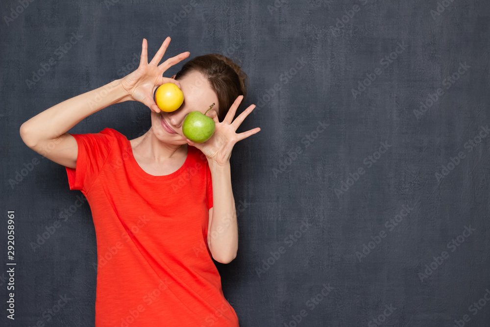 Portrait of happy woman holding ripe apples over eyes Portrait of happy woman holding ripe apples over eyes