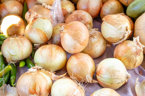 Several yellow onions on display at a local farmers market.