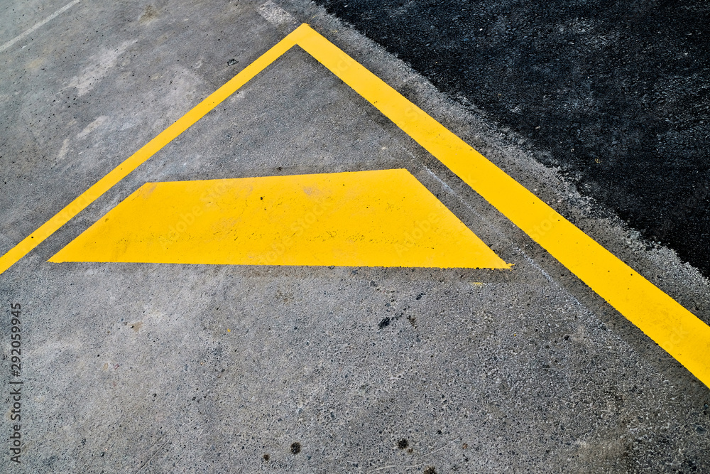 Abstract fragment of yellow road signage - parking lot markings on black road surface.