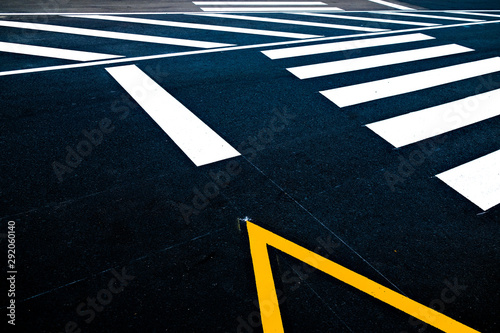 A zebra crossing and a parking lot signage on a black road, an abstract fragment of the pavement.