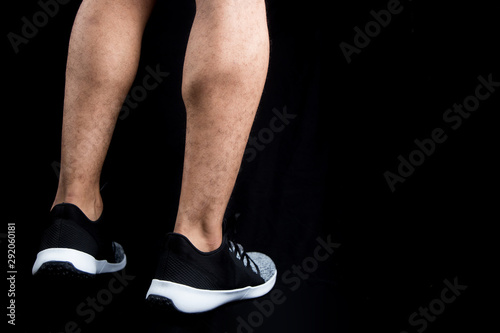 man's legs wearing training shoes on a solid black background with copy space  © Ahmed
