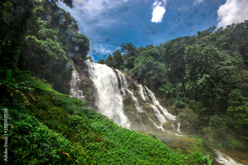 Natural blurred background of waterfalls, fast-flowing currents and water droplets from the wind blowing among the rocks and surrounded by big trees, spontaneous beauty