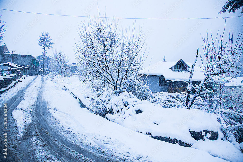 Kashmir, INDIA, January 21, 2019: Snow covered houses and road trees just after the snow fall bad weather concept Kashmir, INDIA, January 21, 2019: Snow covered houses and road trees just after the snow fall bad weather concept