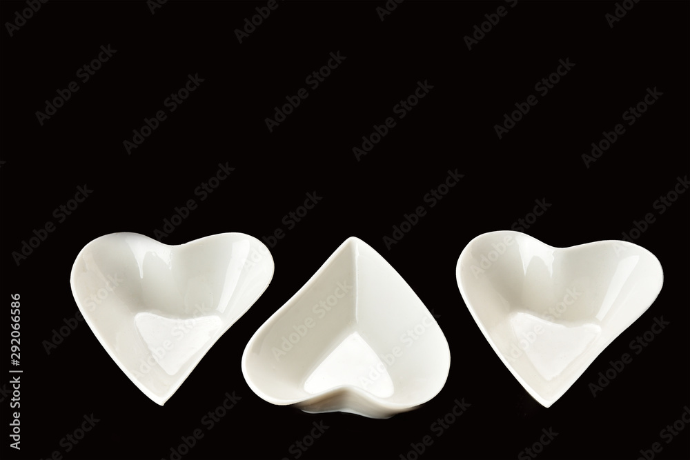 White porcelain heart shape bowl with colorful sauces on black background.