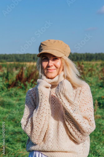 Happy beautiful blond woman walking in a green field