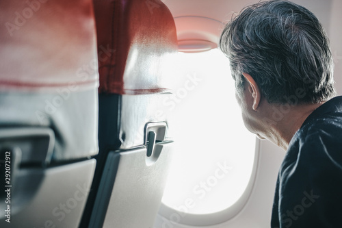 elderly old elder senior woman looking through airplane window