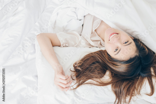Bild auf Leinwand Portrait of young attractive Asian woman lying and relaxing on comfortable bed and looking to camera