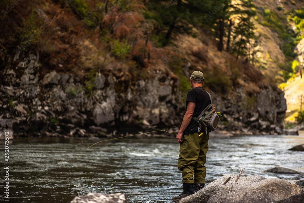 Obraz premium Fly fisherman casting in the mountain stream during the fall season.