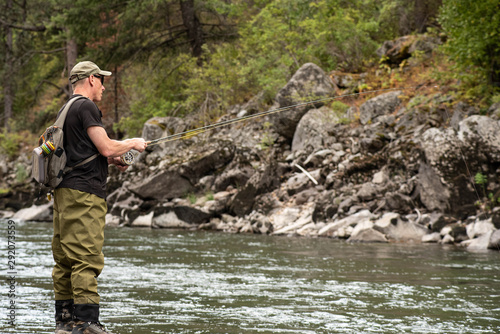 Fly fisherman casting in the mountain stream during the fall season.