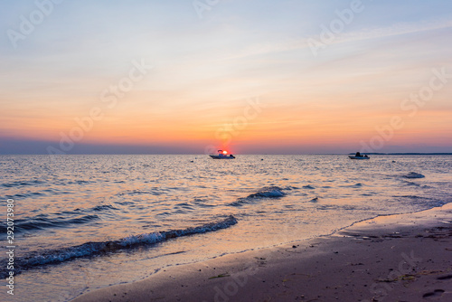 Two boats shield the setting sun over the beach in Cape Cod Massachusetts