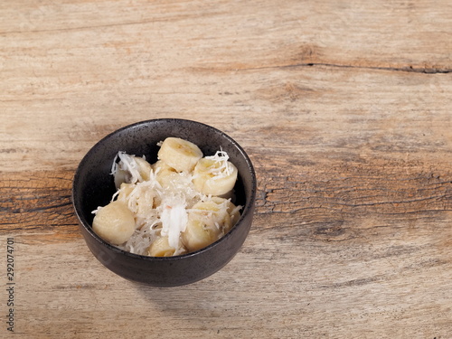 view of Khanom kluay in a dish on wood texture background, Thai dessert local food made of ripe banana mixed coconut and sugar. photo