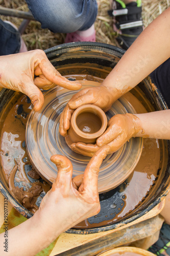 A close up view on ceramic production process on potter's wheel with children. Clay crafts with kids concept.