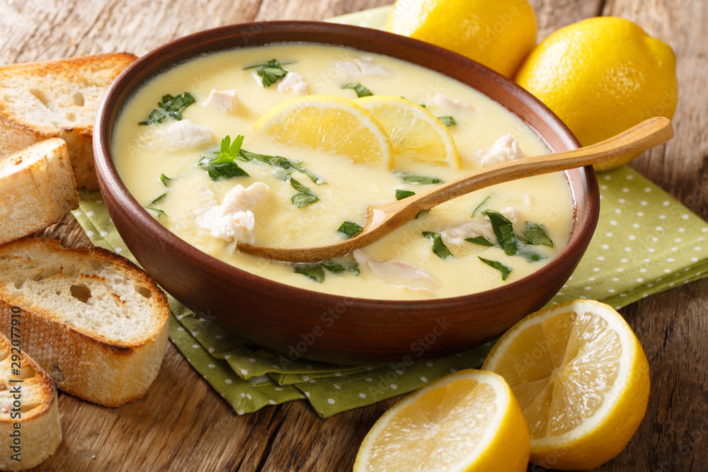 Hot greek lemon soup with chicken close-up in a bowl with bread. horizontal