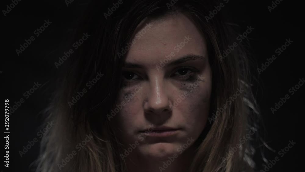 portrait of sad and unhappy young woman with tearful eyes shows quiet by a finger on lips in slow motion into camera, view of female close up
