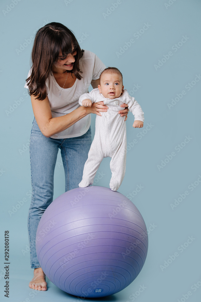 Happy mother doing exercises with her infant child baby on purple yoga ball Happy mother doing exercises with her infant child baby on purple yoga ball