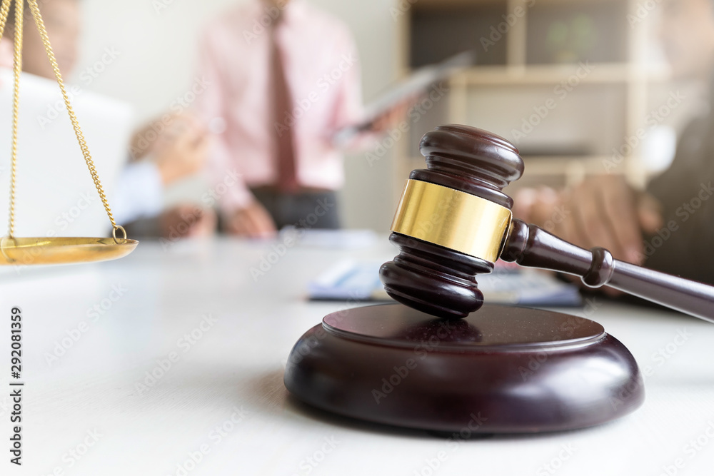 Wooden gavel on table in lawyer's office. Lawyer having team meeting with the client. Concepts of law, advice, legal services. Wooden gavel on table in lawyer's office. Lawyer having team meeting with the client. Concepts of law, advice, legal services.