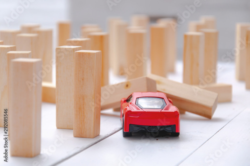 The red toy car overcomes all obstacles in the way and barriers reaching the goal and knocking down obstacles in its path. A red car rides and knocks down wooden poles in its path.
