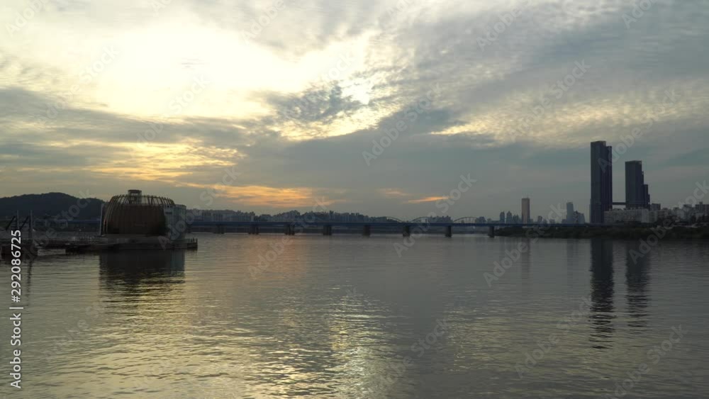 Waterfront Sunset view of the Dongjak bridge and the high rise sixty three square building in Seoul South Korea. The architecture and sky reflect in the river. Part 2 Waterfront Sunset view of the Dongjak bridge and the high rise sixty three square building in Seoul South Korea. The architecture and sky reflect in the river. Part 2