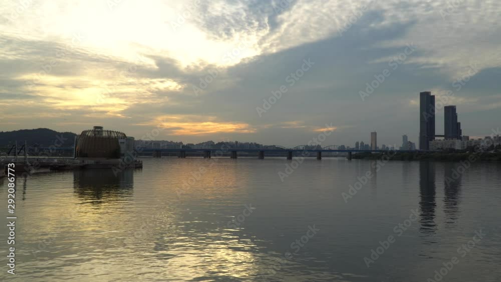 Waterfront Sunset view of the Dongjak bridge and the high rise sixty three square building in Seoul South Korea. The architecture and sky reflect in the river. Part 3 Waterfront Sunset view of the Dongjak bridge and the high rise sixty three square building in Seoul South Korea. The architecture and sky reflect in the river. Part 3