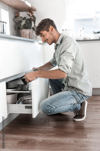 attractive man taking plates out of the kitchen table