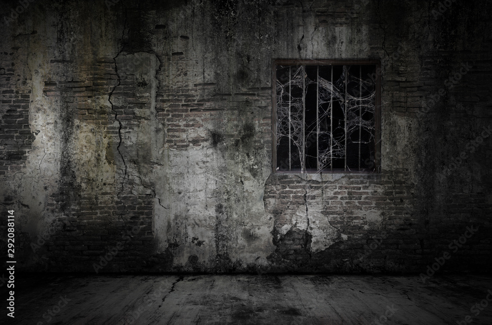 Fototapeta Okna i zardzewiałe kraty pokryte pajęczyną lub pajęczyną na więziennej ścianie z starych cegieł i zakurzonej podłodze, koncepcja horroru i Halloween