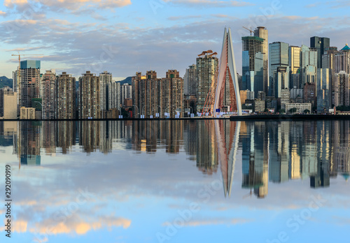 Chongqing skyline and modern urban skyscrapers with water reflection at sunset China.