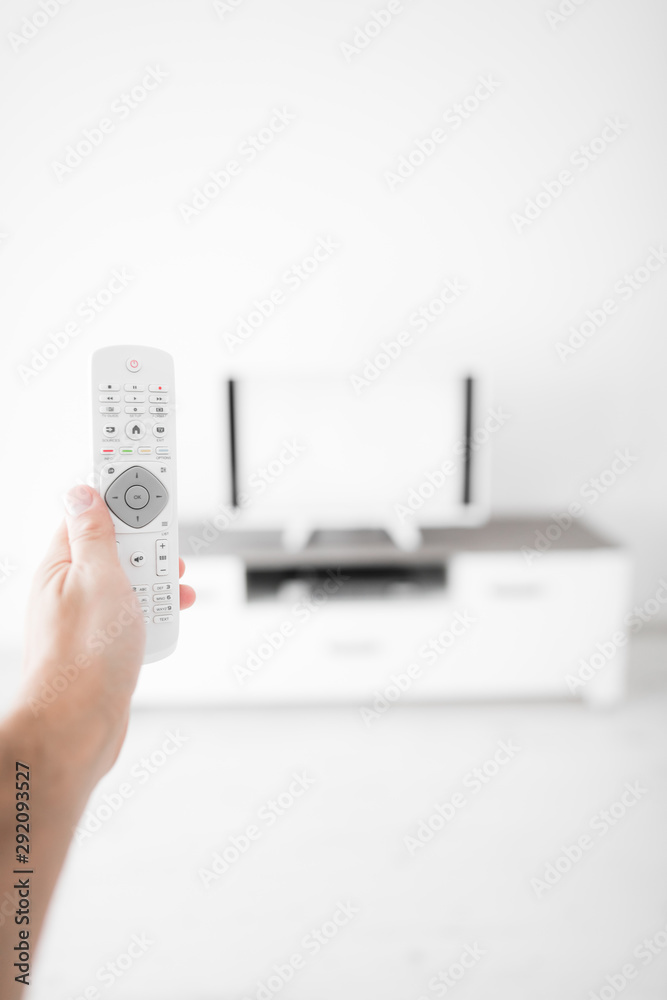 Hand holding TV remote controller with a modern television set. Hand holding TV remote controller with a modern television set.