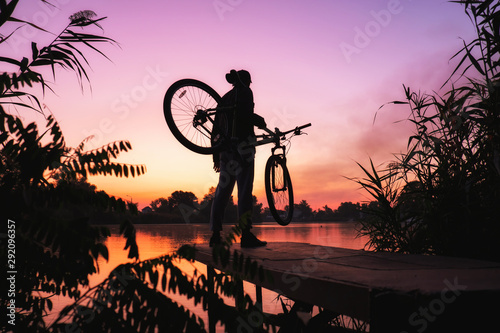 Man with a bicycle on the lookout admires the sunrise or sunset. Sport, active lifestyle. Beautiful colors at dawn