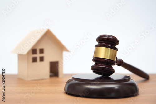 Auction or law concept. Miniature House on wooden table and judge gavel.