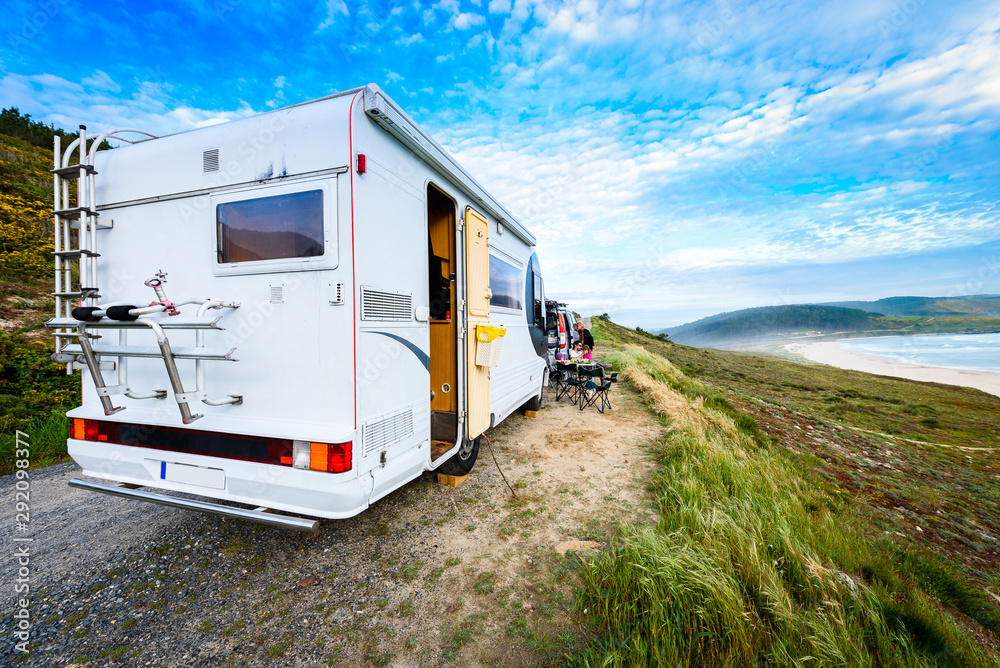 Motorhome RV and campervan are parked on a beach. Motorhome RV and campervan are parked on a beach.