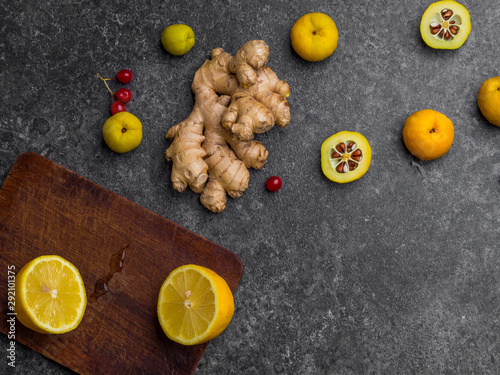 ginger root, lemon on wooden board, cydonia, red berries on grey background