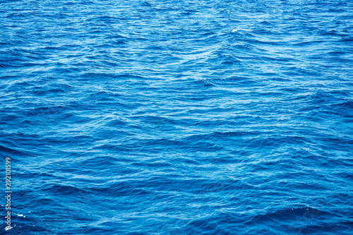 Ocean blue empty water surface background with small waves.
