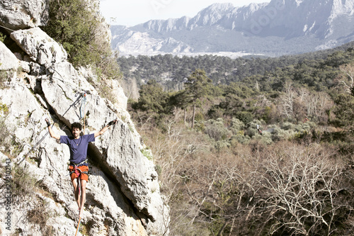 A man is walking along a stretched sling. Highline in the mountains. Man catches balance. Performance of a tightrope walker in nature. Highliner on the background of the mountains.