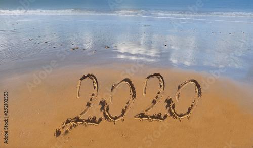 2020 handwritting on the sand to the beach with ocean background