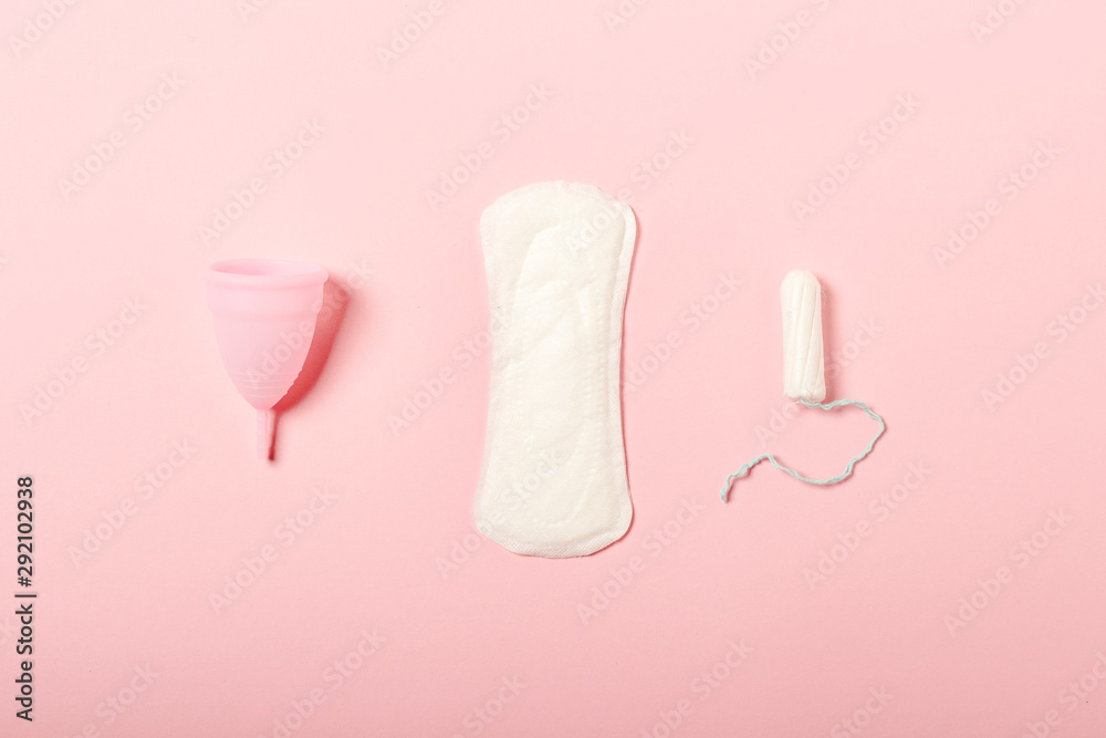 Menstrual cup, sanitary pad and swab on a pink background. Concept of menstruation, the choice between feminine hygiene products. Flat lay, top