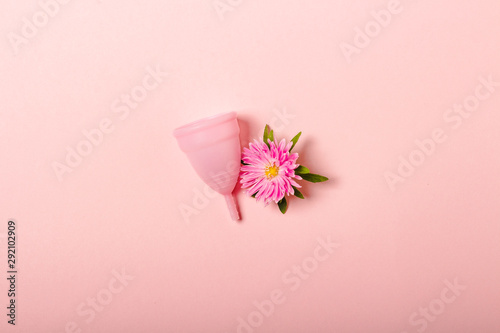 Menstrual cup and flower on a pink background. The concept of menstruation. Flat lay, top photo