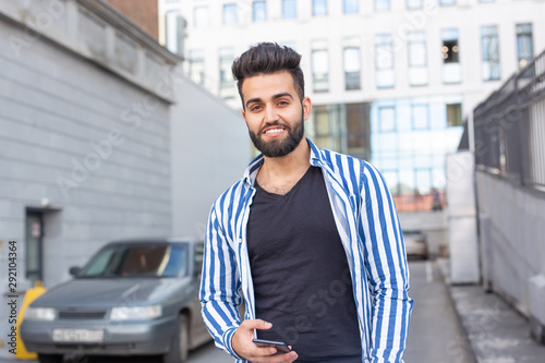 Modern arab young man with mobile phone in the street. Outdoor portrait.