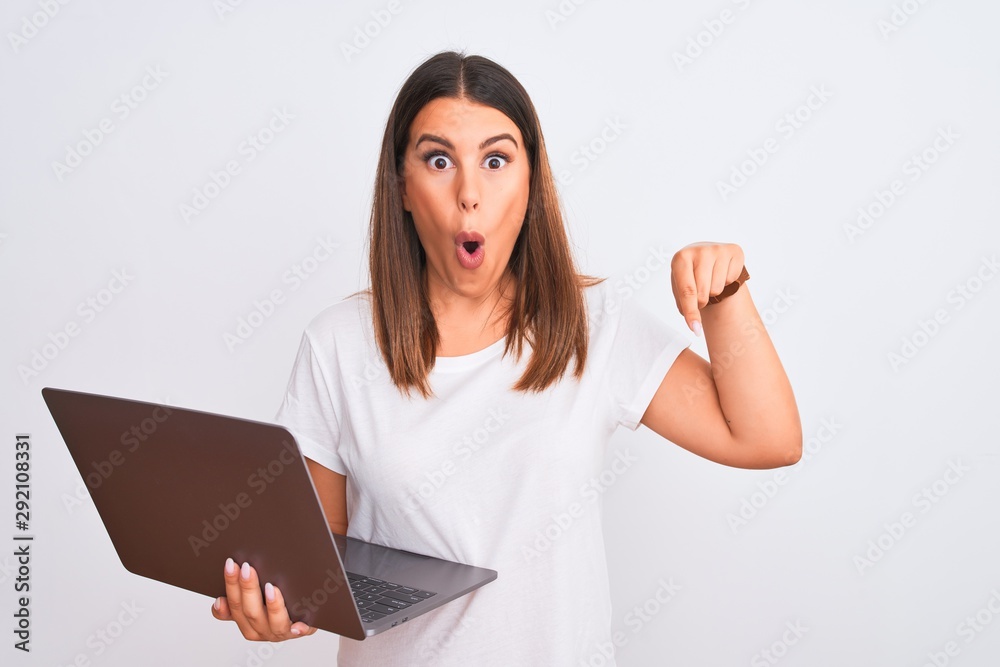 Beautiful young woman working using computer laptop over white background Pointing down with fingers showing advertisement, surprised face and open mouth Beautiful young woman working using computer laptop over white background Pointing down with fingers showing advertisement, surprised face and open mouth