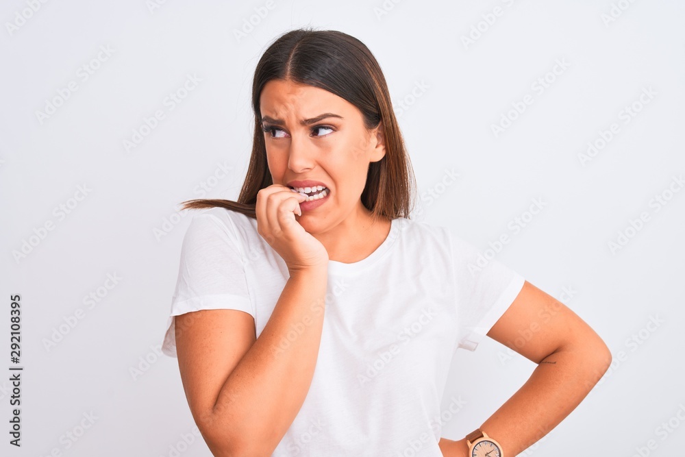 Portrait of beautiful and young brunette woman standing over isolated white background looking stressed and nervous with hands on mouth biting nails. Anxiety problem. Portrait of beautiful and young brunette woman standing over isolated white background looking stressed and nervous with hands on mouth biting nails. Anxiety problem.